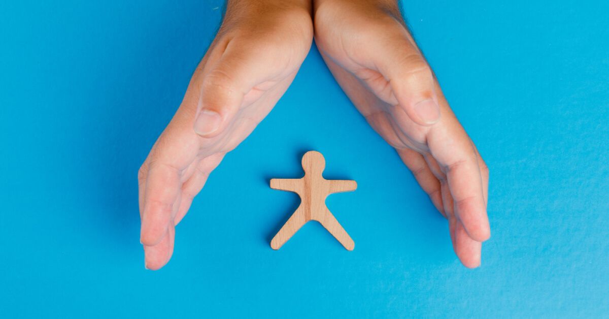 A hand taking care wooden human figure