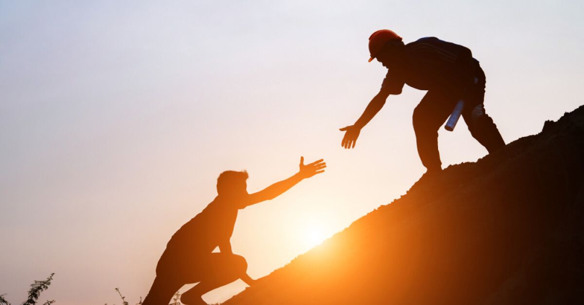 Silhouette of people climbing an inclined terrain