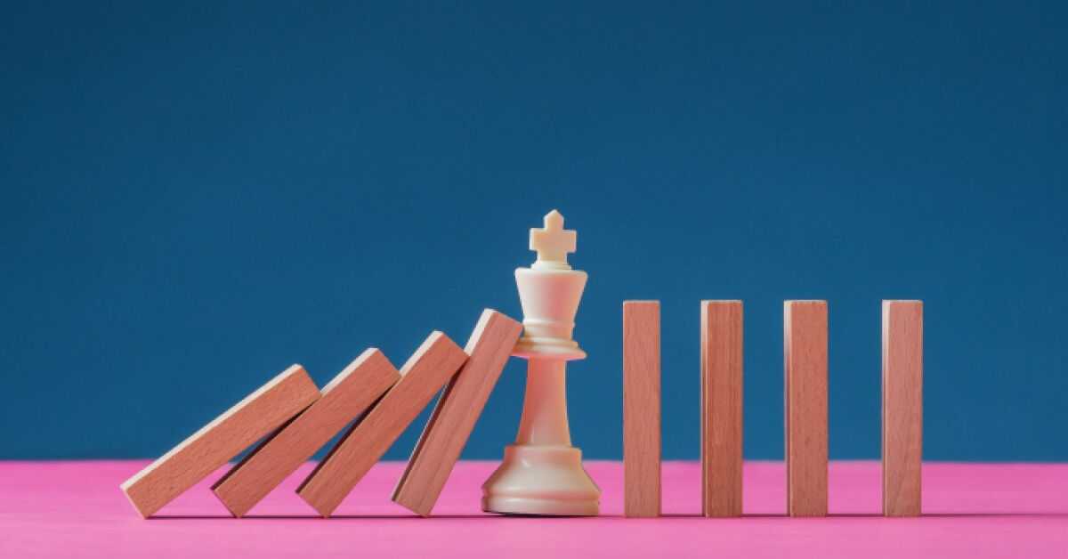 A chess figure standing in the middle of falling domino