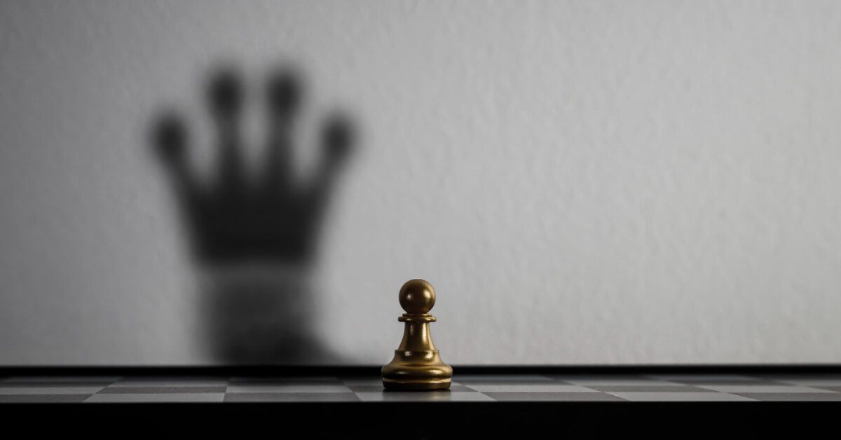 A gold pawn on a chessboard, casting a king shadow