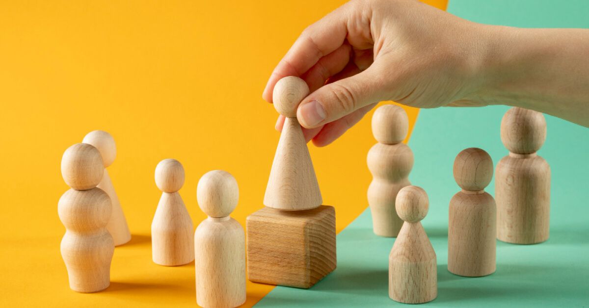 Person placing a pawn on top of a wooden block