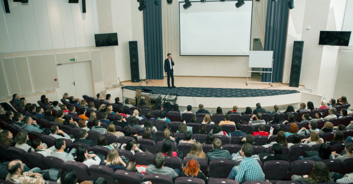 People in a conference hall, paying attention to a speaker